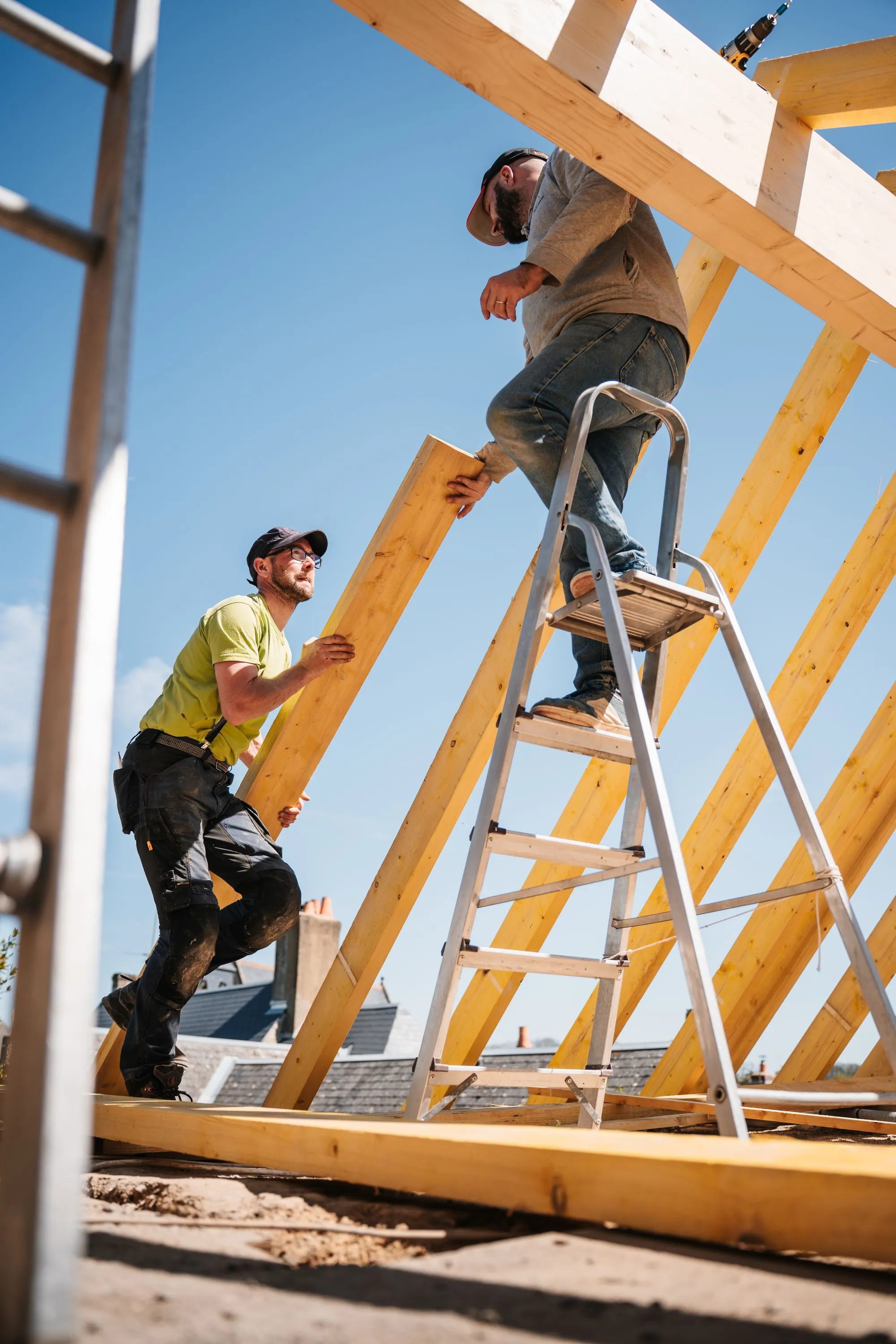 A roofer carrying timber up a ladder at a house