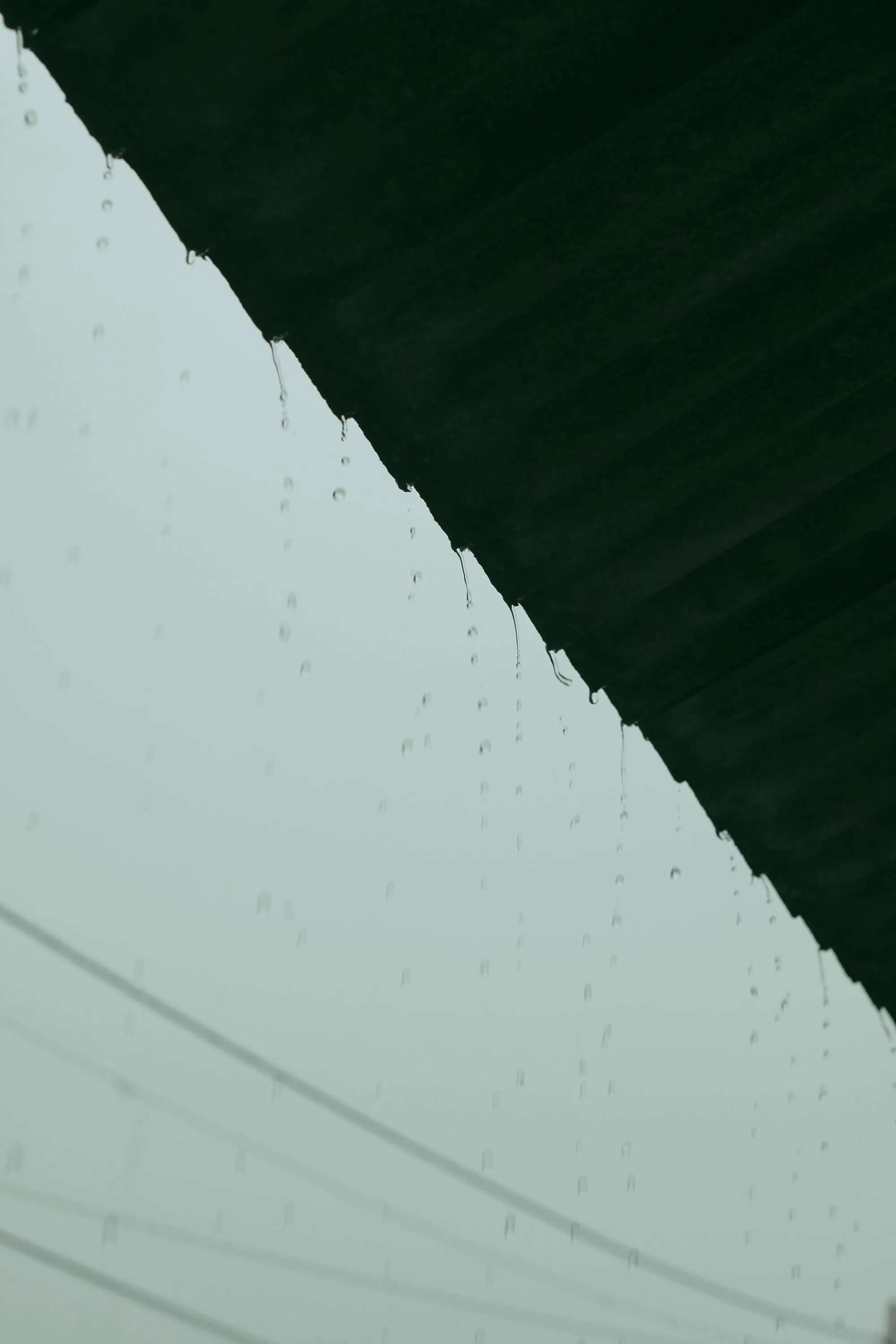 Rain spilling from the edge of a roof into the gutter line